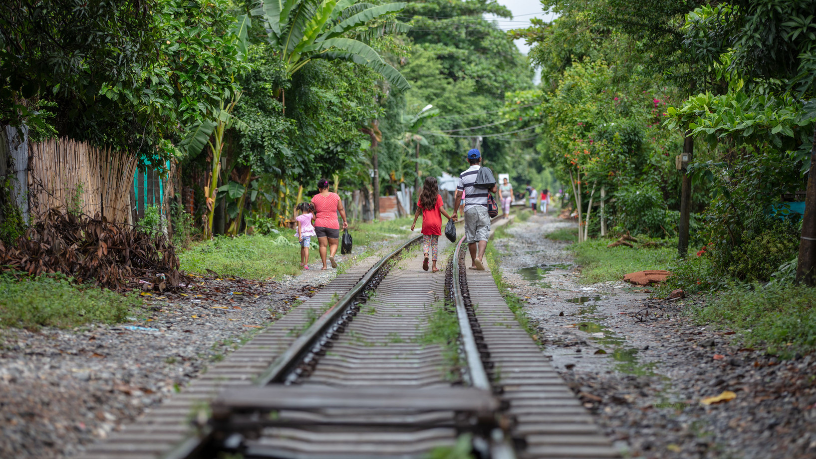 Bild: Personen gehen entlang eines Zuggleises.